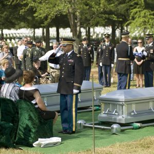 Army Chaplain (Capt.) John Gabriel salutes a folded American flag that was presented to Virginia Doolittle (seated), a surviving family member of 1st Lt. Joseph J. Auld, one of the seven Airmen who were interned July 15, 2010 at Arlington National Cemetery, Va. (DOD photo/Michael Tolzmann)